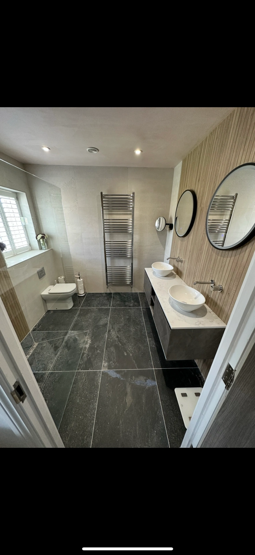 Spacious ensuite with slate floor, oak feature wall and twin vessel basins