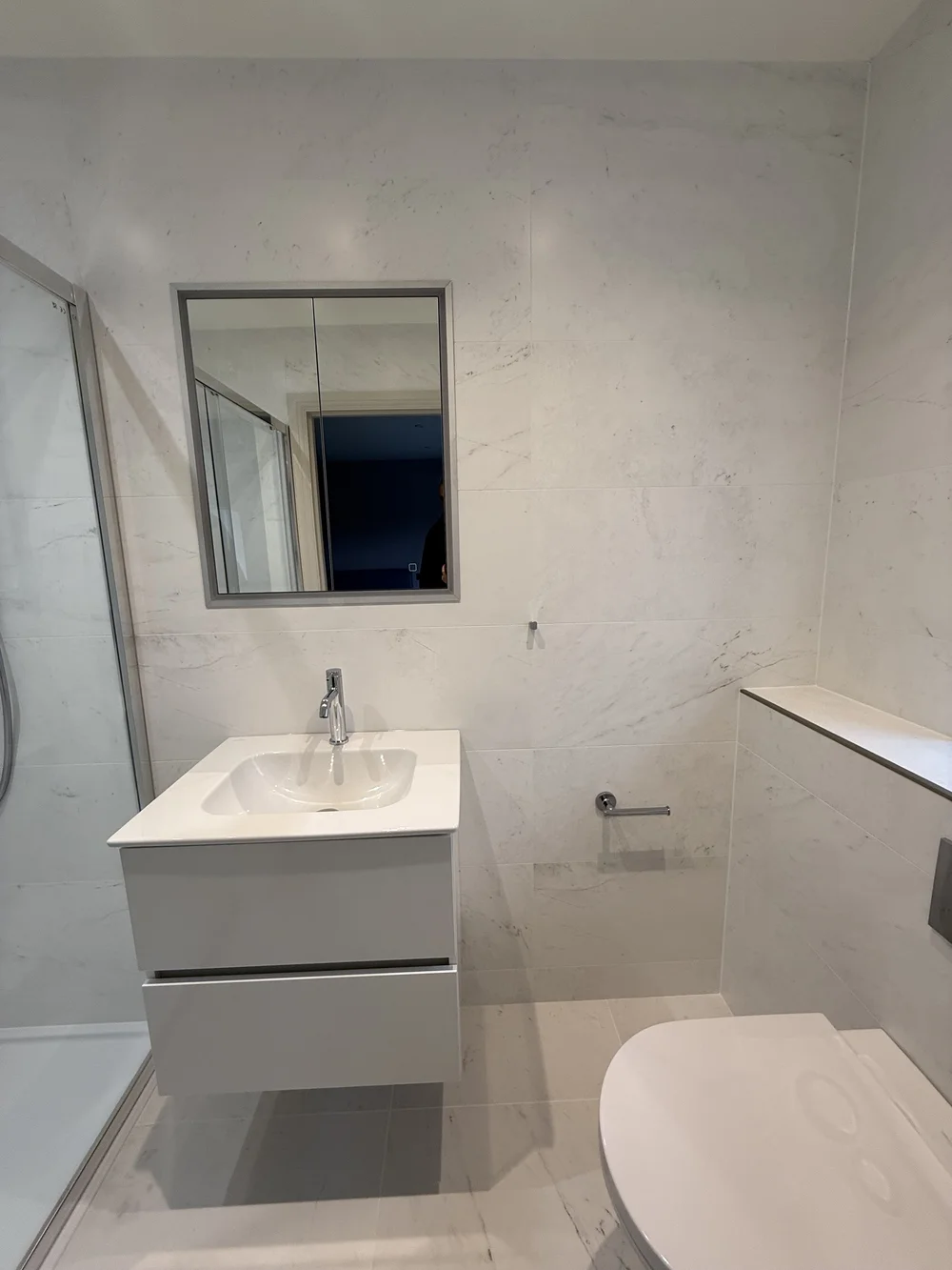 Compact marble ensuite with wall-hung vanity and back-to-wall WC — bathroom fitting