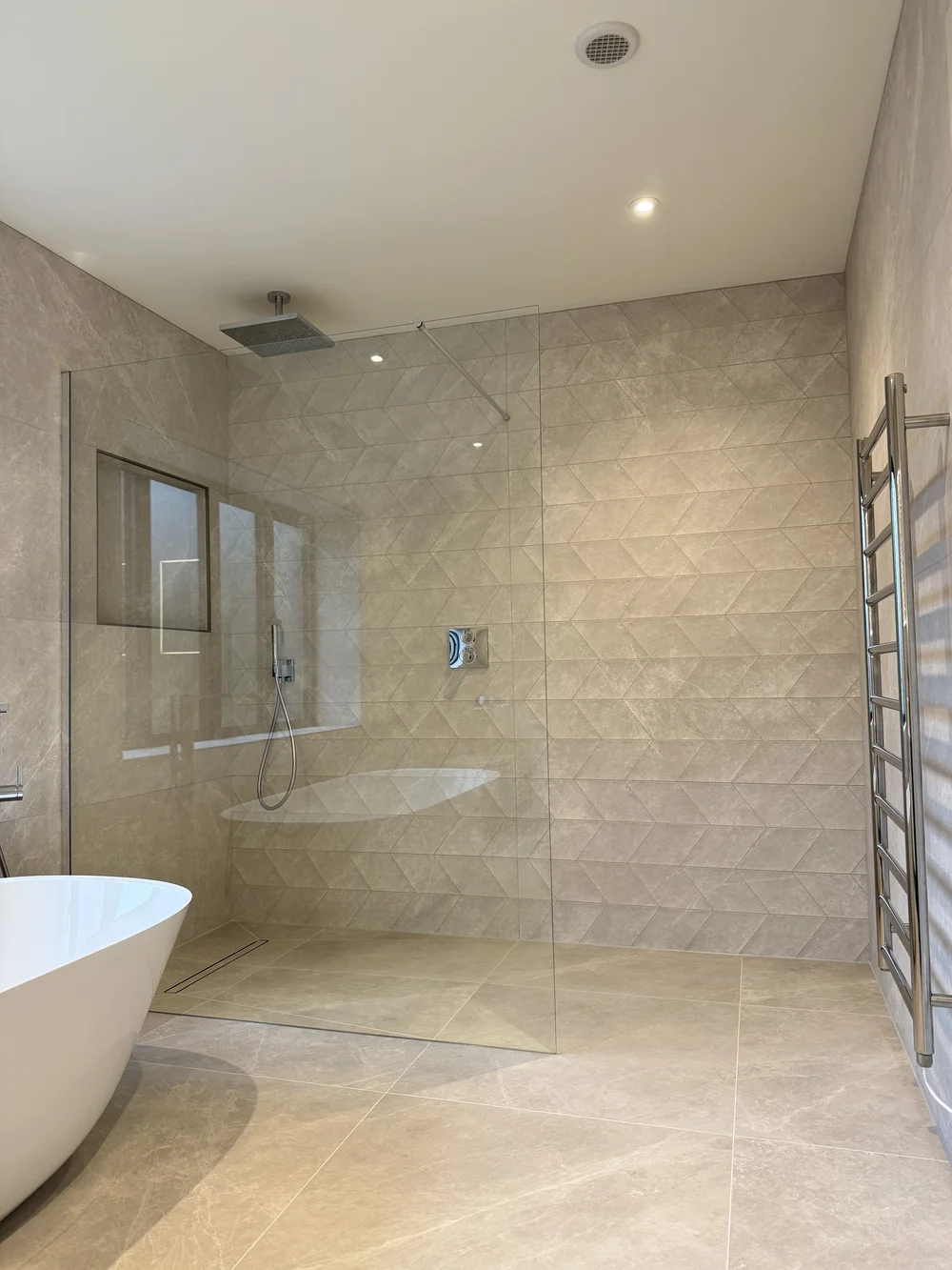 Luxury wet room with freestanding bath, rainfall shower and chevron tiling
