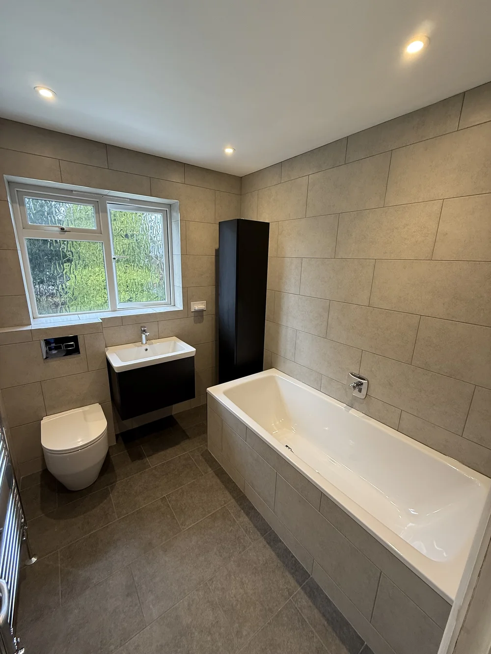 Fitted family bathroom with black vanity, tall storage and built-in bath — bathroom installers