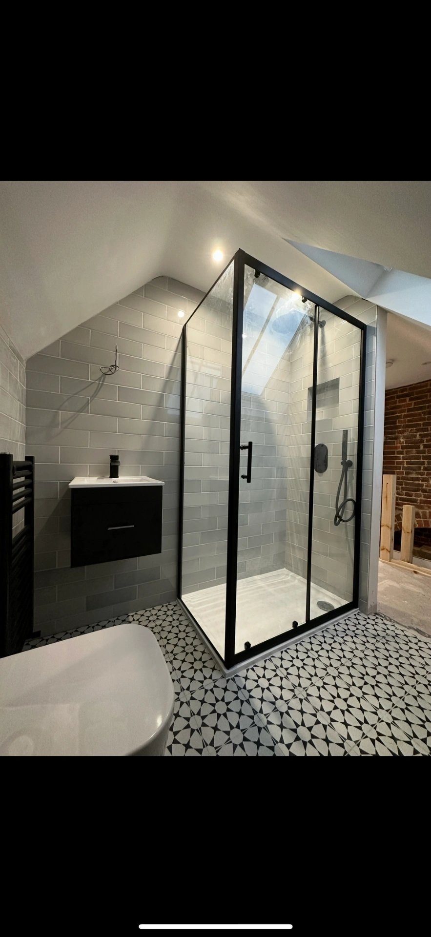 Loft ensuite with matte-black framed shower enclosure and patterned floor — Reading