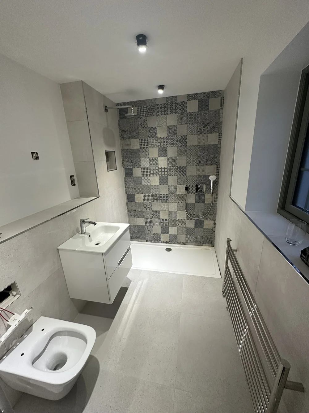 Modern shower room with patchwork feature tiles, white vanity and heated ladder rail — bathroom renovation