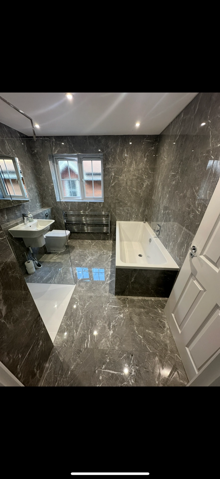 Grey marble family bathroom with double-ended bath and chrome towel rail