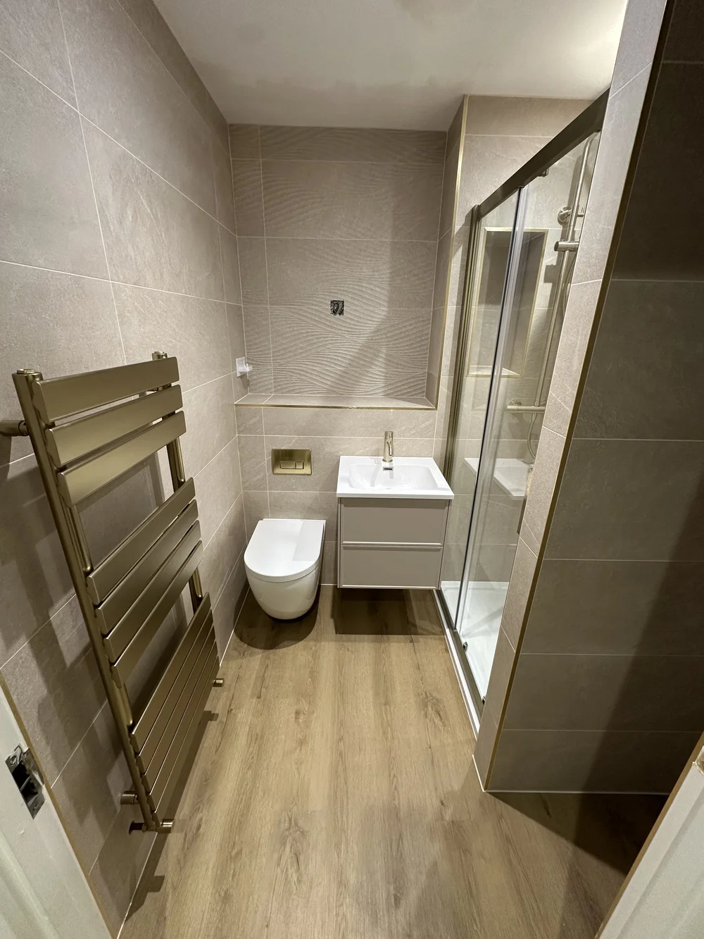 Modern shower room with brushed brass trim, sliding glass door and designer radiator — bathroom fitting