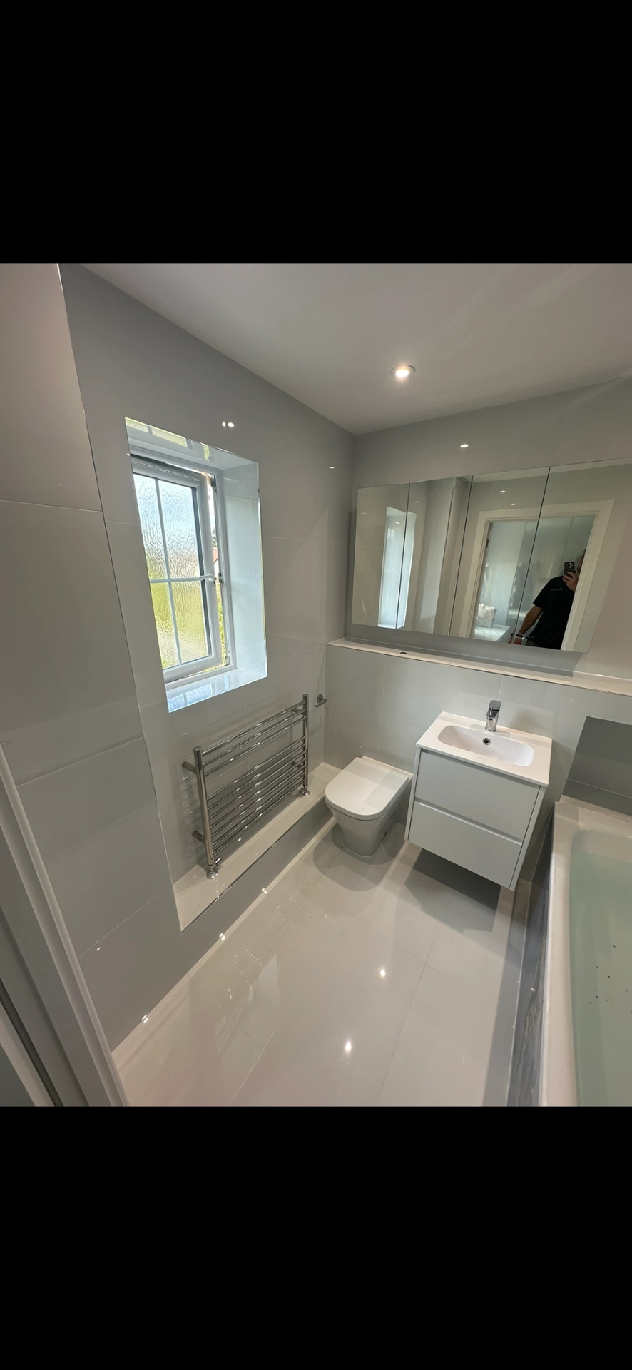 Bright white family bathroom with floating vanity, mirrored cabinet and gloss floor tiles — bathroom installation in Reading