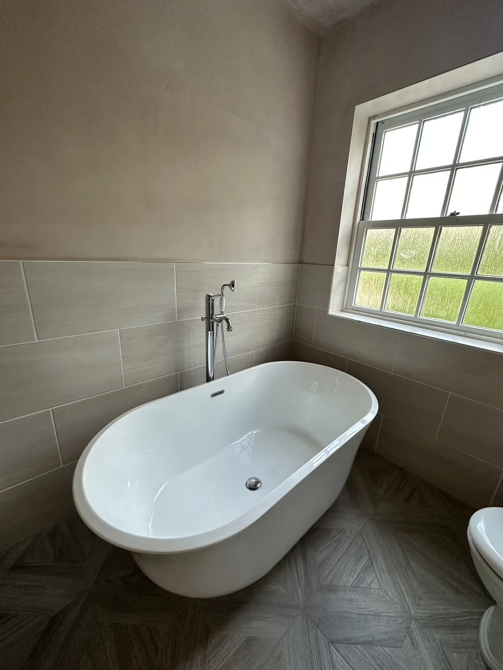 Traditional freestanding double-ended bath with chrome floor-mounted mixer and parquet floor — bathroom installation