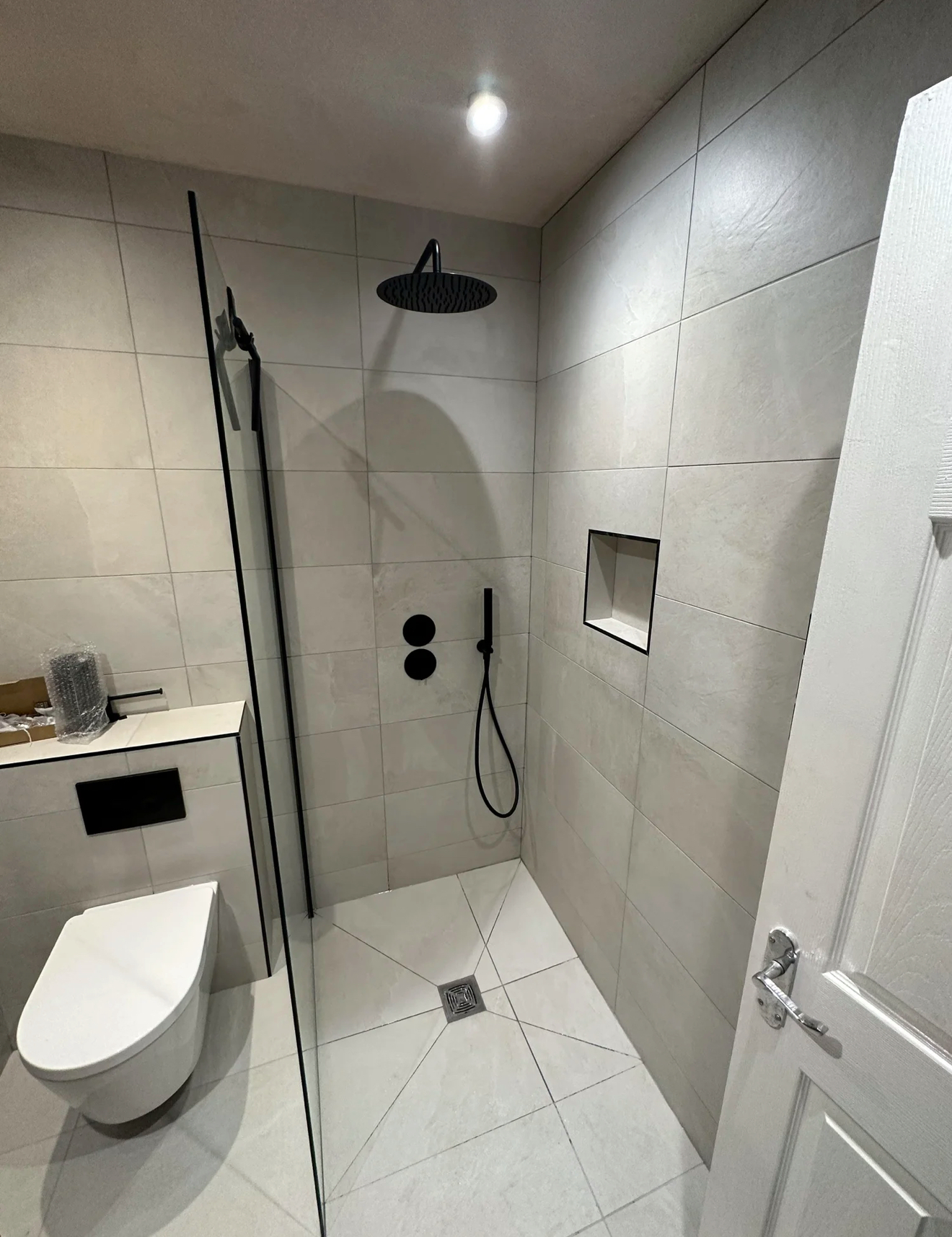 Compact wet room with black rainfall shower and wall-hung WC in Reading