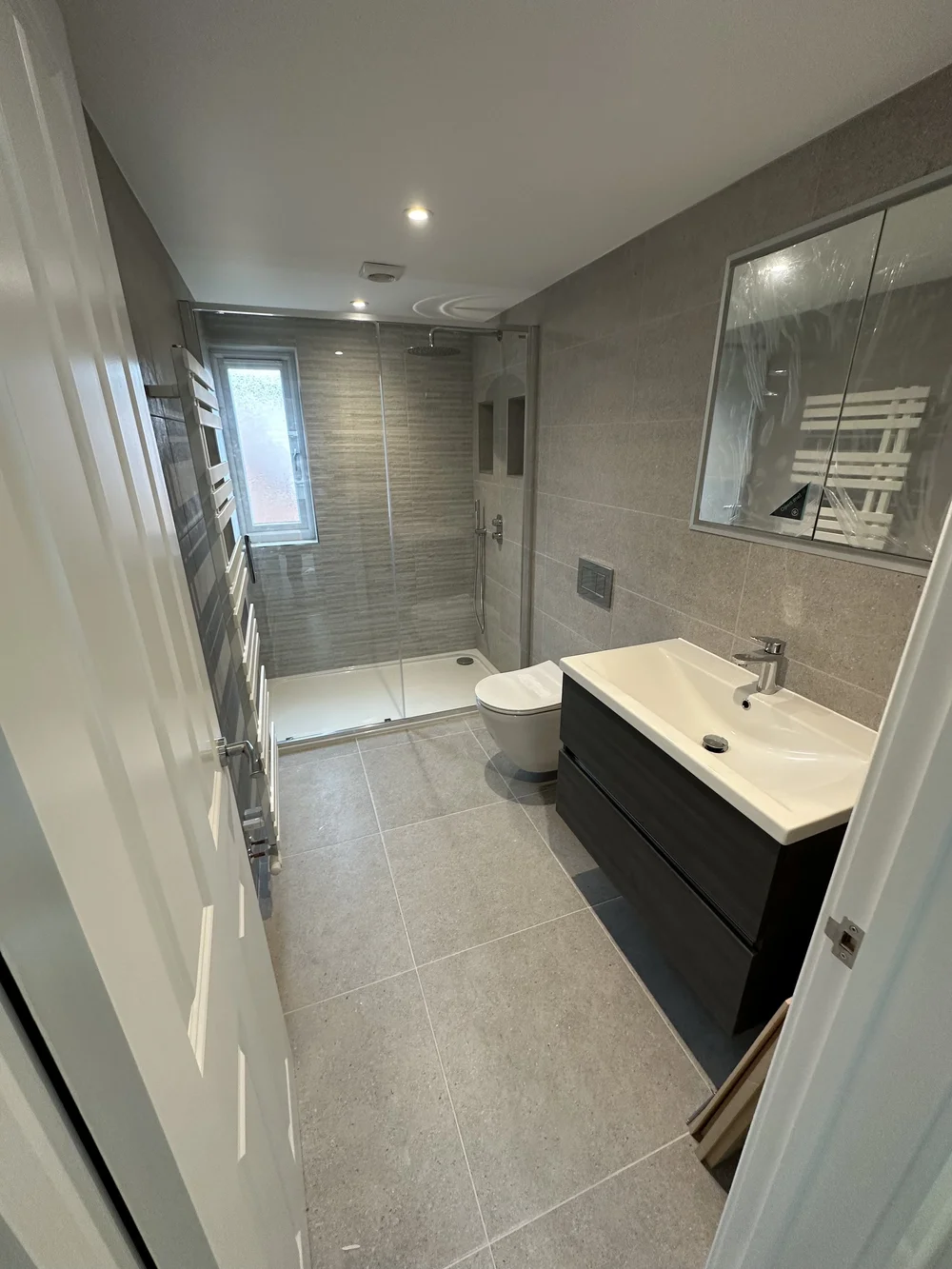 Grey stone-tiled shower room with graphite vanity and glass shower enclosure — bathroom installation