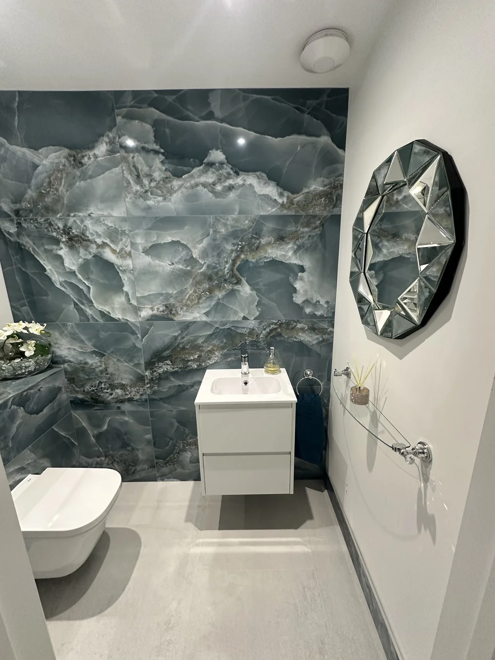 Luxury cloakroom with blue onyx feature wall, wall-hung WC and jewel-cut mirror — bathroom installation