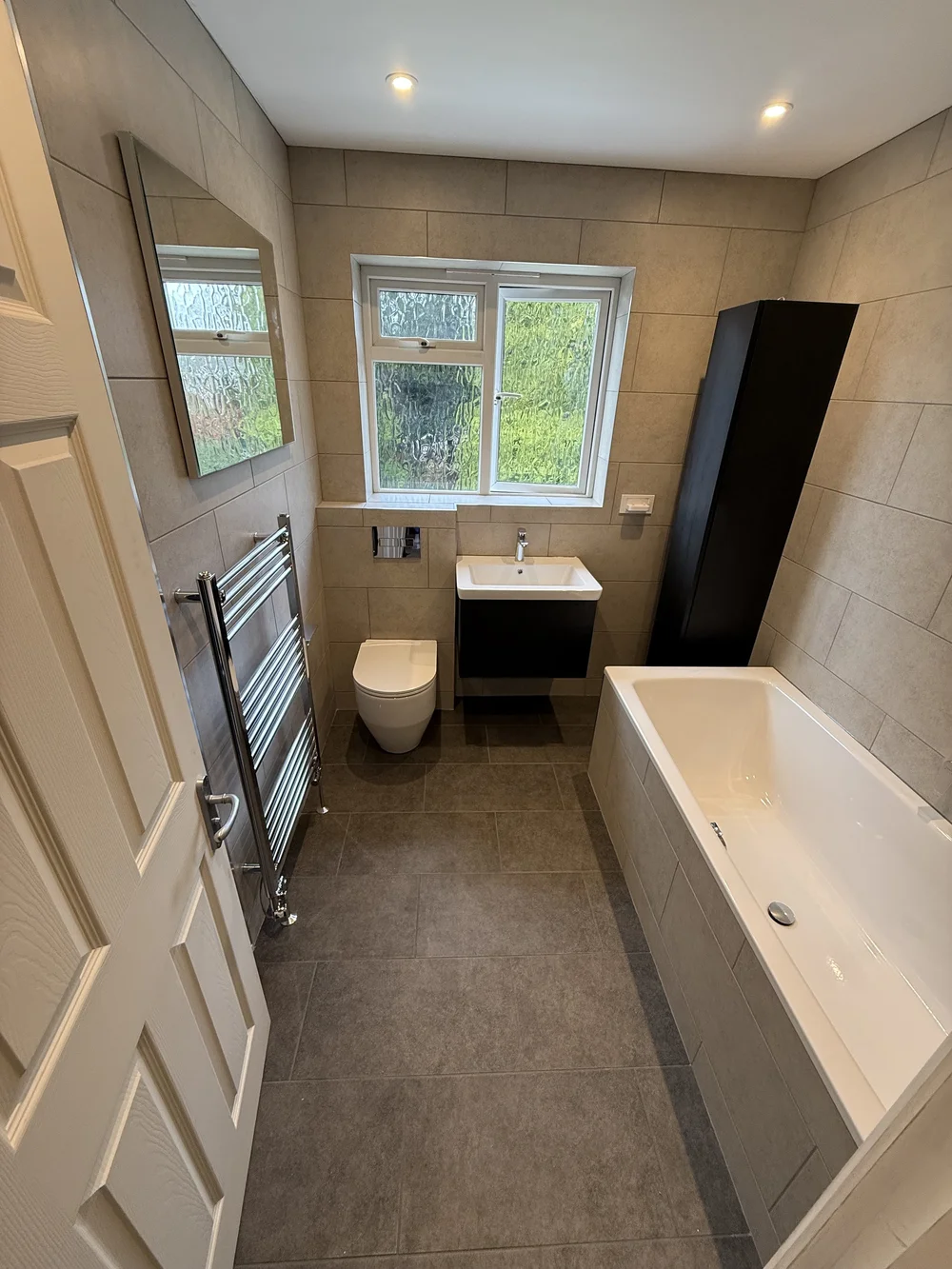 Compact family bathroom with black vanity, wall-hung WC and built-in bath — bathroom installation in Reading