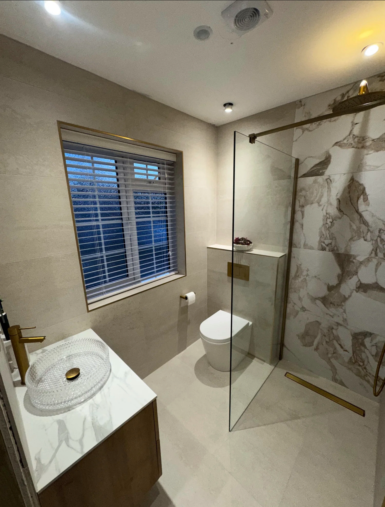 Luxury wet room with marble feature wall and brushed brass fittings in Reading
