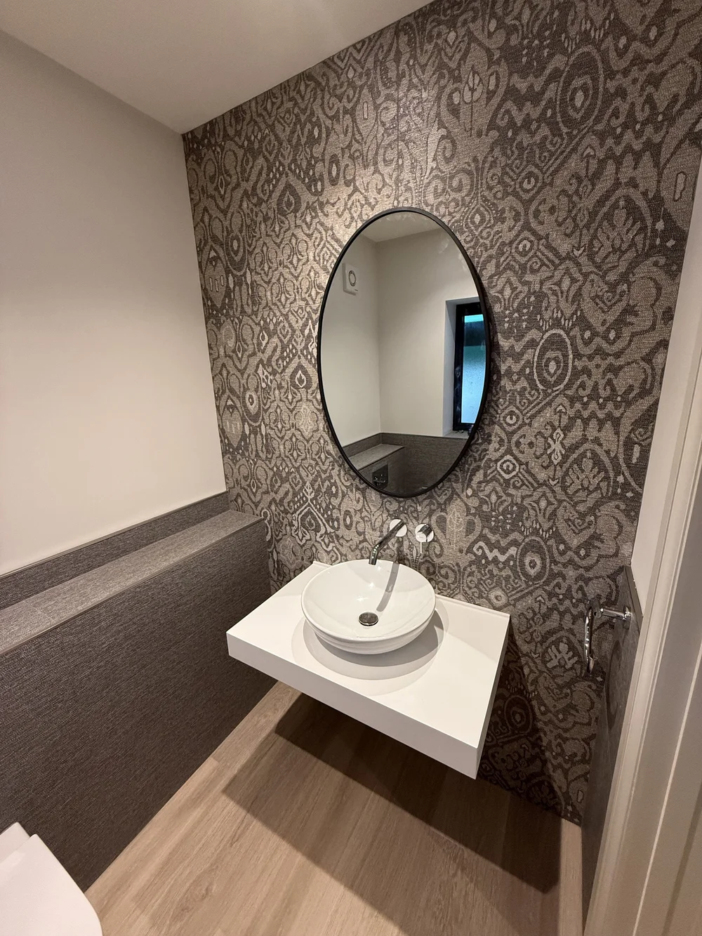 Feature-wall cloakroom with round black mirror and vessel basin — bathroom design