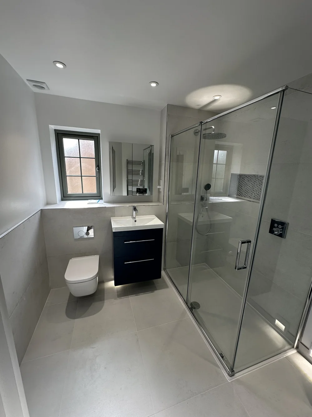 Fitted shower room with navy vanity, wall-hung WC and large glass shower enclosure — bathroom installation in Reading