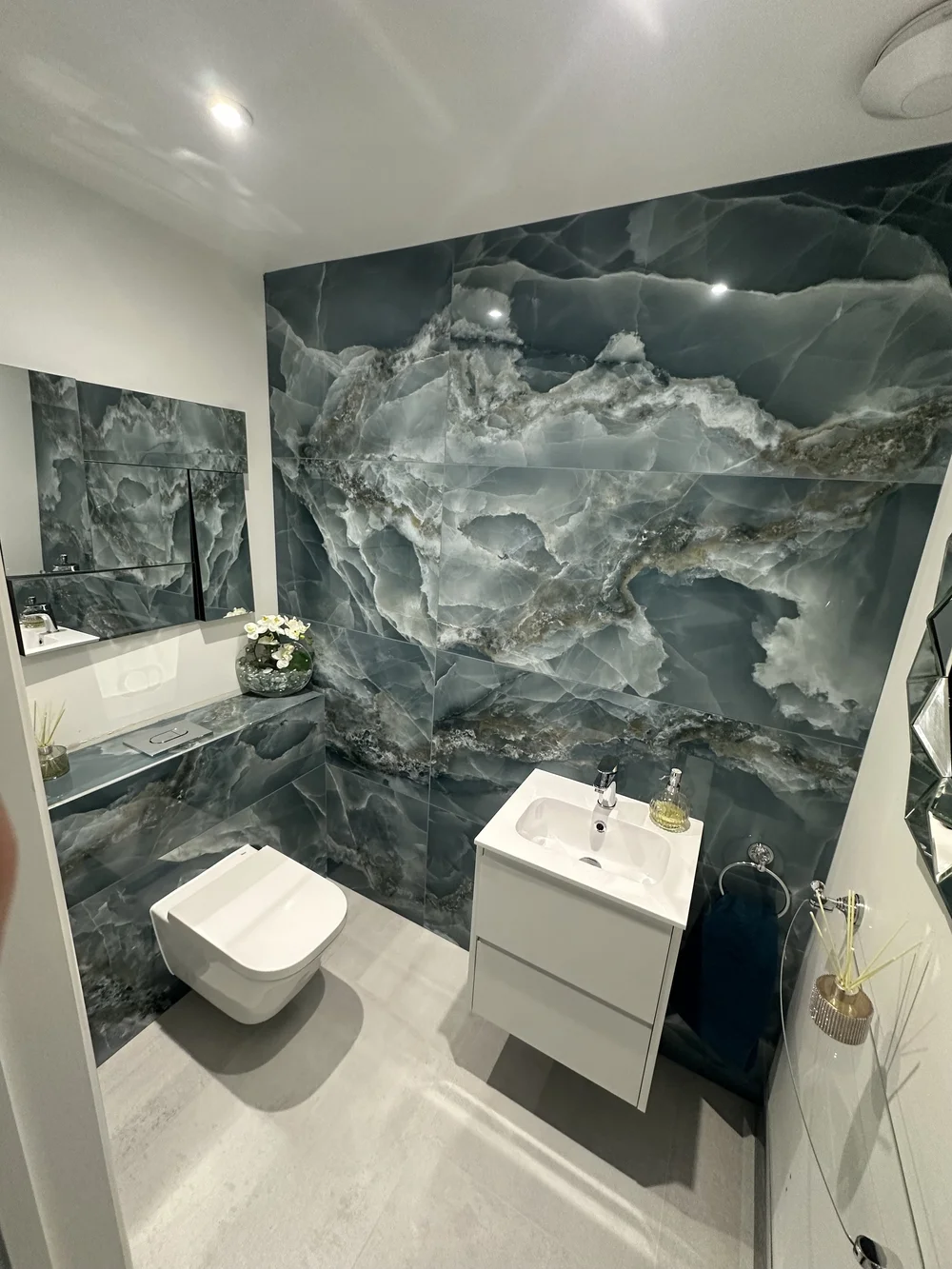 Cloakroom with blue onyx feature wall, wall-hung WC and floating white vanity — bathroom design