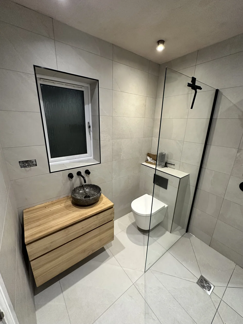 Wet room with oak floating vanity, stone basin and glass walk-in screen — wet room installation