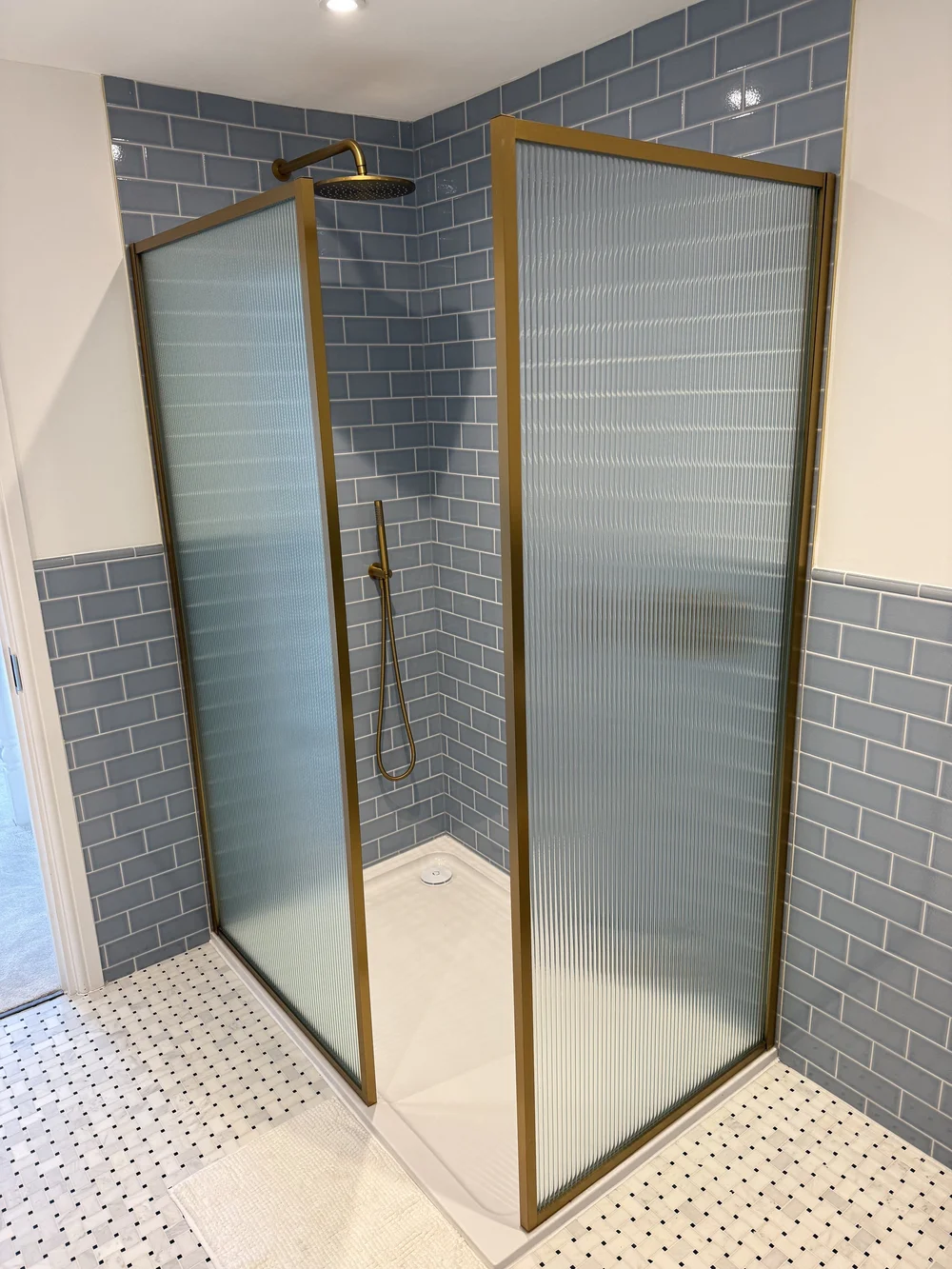 Blue metro tile walk-in shower with brushed brass fluted screens — bathroom fitting