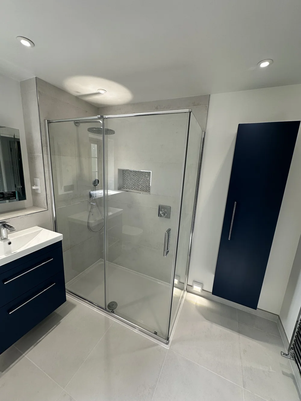 Contemporary shower room with navy wall cabinet, floating vanity and walk-in shower — bathroom installation