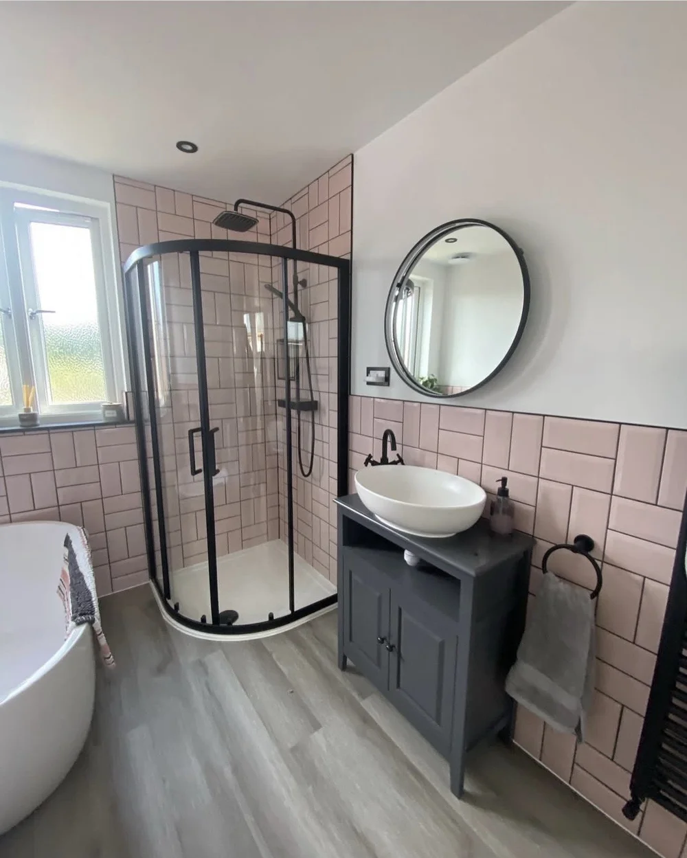 Pink metro-tiled bathroom with black-framed quadrant shower, freestanding bath and vessel basin — bathroom renovation