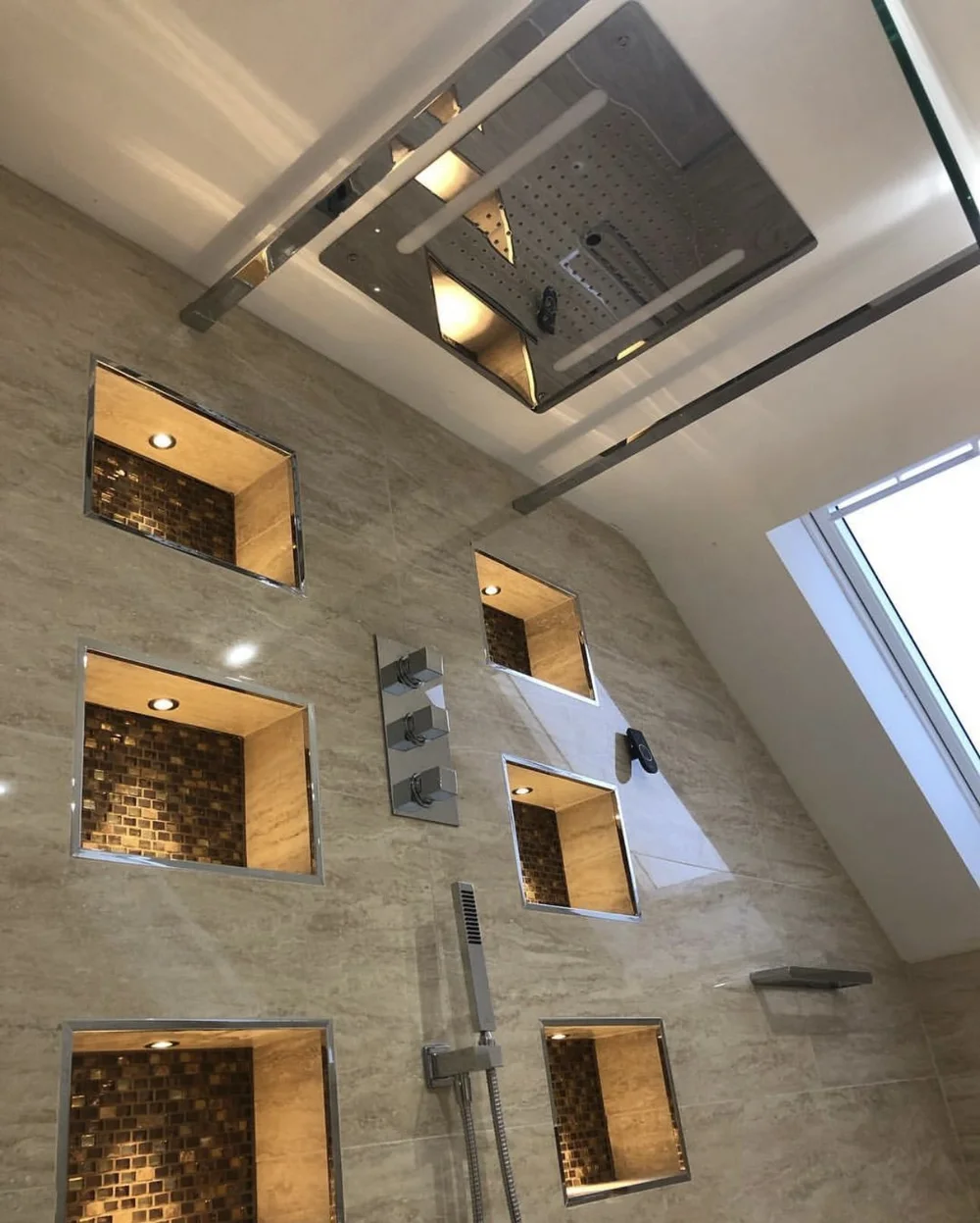 Ceiling rainfall panel with LED strip lighting over travertine walk-in shower — luxury bathroom installation