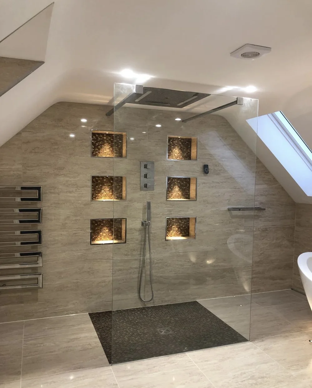 Luxury loft wet room with travertine walls, mosaic niches and frameless glass screen — bathroom fitting